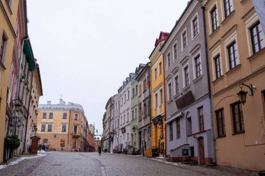 Lublin, Polonya, 25 Kasım 2025: Eski şehir Lublin 'de binalar bulutlu bir gökyüzünün altında cadde boyunca sıralanır. Olay yeri, etrafta az kişinin olduğu sessiz bir bölgeyi gösteriyor..