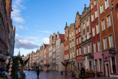 Gdansk, Polonya, 27 Kasım 2025: İnsanlar Polonya 'nın Gdansk kentinin işlek caddelerinde yürüyor, güneş ışıl ışıl parlarken etrafları renkli binalar ve dükkanlarla çevrili. Long Caddesi Ulica Dluga