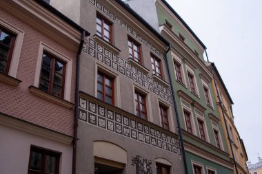 Lublin, Polonya, 25 Kasım 2025: Lublin 'de tarihi yapılar dar bir cadde üzerindedir. Mimari çeşitli stil ve renkleri gösteriyor. Fenerler girişte asılı..