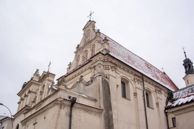 Polonya, St. Joseph Kilisesi, Lublin. Çatısı karla kaplı küçük bir kasabada tarihi bir kilise duruyor. Sahne bulutlu gökyüzü ile kışın geçer. Kilisenin detayları.