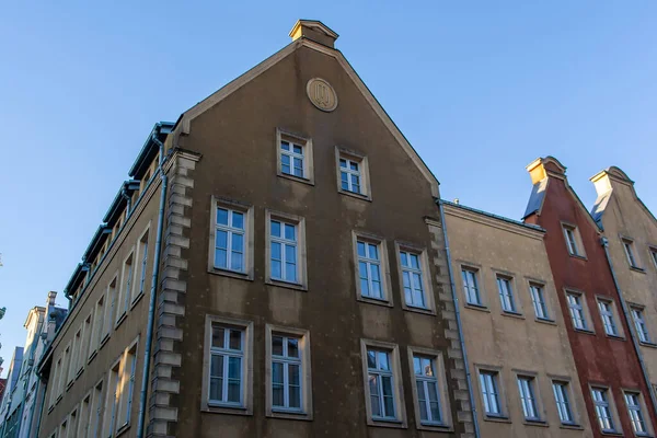 Açık mavi gökyüzünün altında farklı cephelere sahip eski binaların manzarası. Yapılar bölgenin tipik tasarımını gösteriyor. Gdansk 'ta tarihi bir bölgede renkli binalar cadde boyunca diziliyor.
