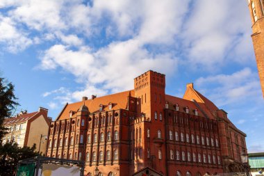 Kırmızı tuğla bina, Polonya 'nın Gdansk kentindeki mavi gökyüzüne karşı mimarisini sergileyen bir kuleye sahiptir. Sahne şehirde bir anı yakalar..