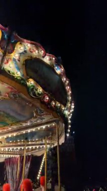 Gdansk, Polonya, 27 Kasım 2025: Parlak ışık ve dekorasyonlarla dolu bir atlıkarınca, insanların gün batımında festival atmosferinin tadını çıkardıkları bir şehir parkında dönüyor. Noel piyasa sahnesi