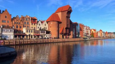 Gdansk, Polonya, 27 Kasım 2025: Eski kasaba ve ünlü vinç, Polonya Zuraw. Motlawa nehrinin manzarası. İnsanlar gün boyunca Gdansk 'ta nehre bakan eski binalara bakarken su kenarında yürürler..