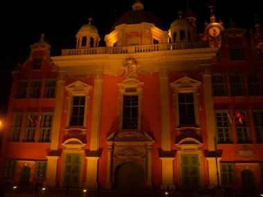 Gece bir şehir meydanında tarihi bir bina duruyor. Işıklar mimarinin üzerinde parlıyor, kulelerin ve kubbelerin dikkatini çekiyor. Polonya, Gdansk 'taki Kraliyet Şapeli.