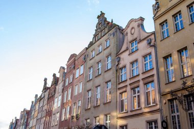Gece boyunca Gdansk 'ta bir sokakta pencereli uzun binalar sıralanır. Gökyüzü güneş batarken berrak.
