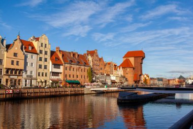 Gdansk, Polonya, 27 Kasım 2025: Eski kasaba ve ünlü vinç, Polonya Zuraw. Motlawa nehrinin manzarası. İnsanlar gün boyunca Gdansk 'ta nehre bakan eski binalara bakarken su kenarında yürürler..