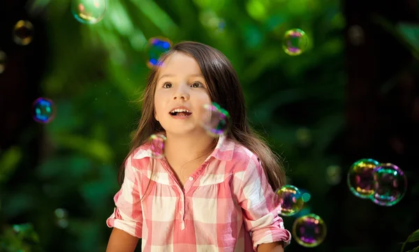 Девочка смотрит на мыльные пузыри — ストック写真