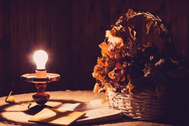 Eski bir lambayla aydınlatılmış bir sepet çiçek.