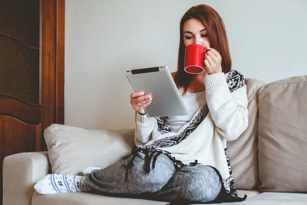 Mujer sentada en el sofá con tablet y café en la mano — Foto de Stock