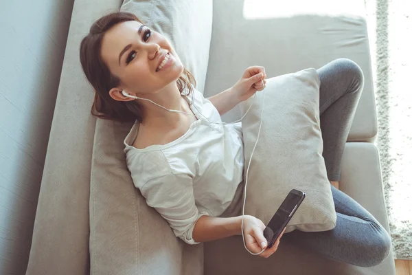 Chica escuchando música mientras se sienta en el sofá — Foto de Stock