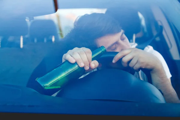 A man driving a car with a bottle of beer — Stock Photo, Image