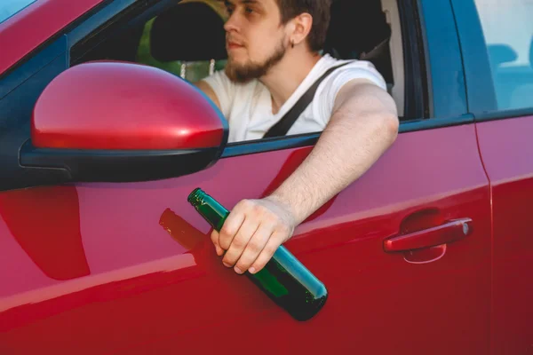 A man driving a car with a bottle of beer — Stock Photo, Image