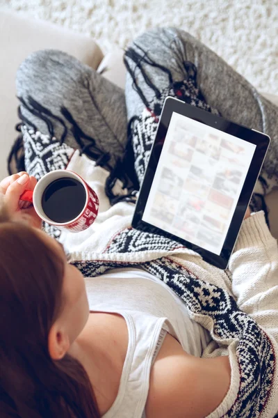 Mujer sentada en el sofá con tablet y café en la mano — Foto de Stock