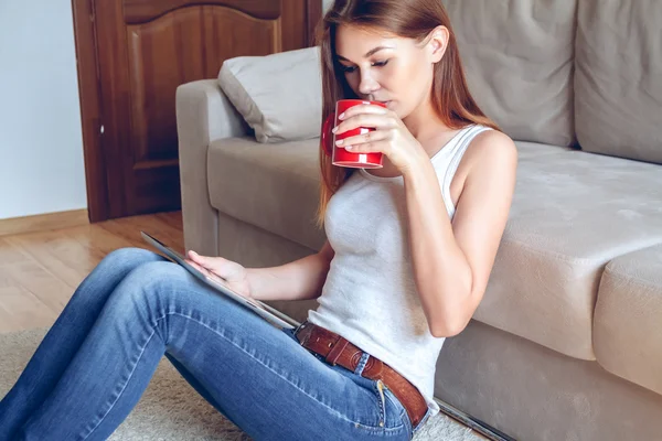 여자 손에 태블릿 및 커피와 함께 소파에 앉아 — 스톡 사진