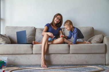 Küçük çocuk ve annesi kanepede birlikte oynuyorlar.