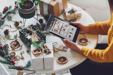 El yapımı Noel süslemeleri olan tabletli bir kadın eli.