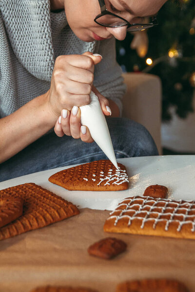 Маленький мальчик с мамой украшают рождественский пряничный домик вместе