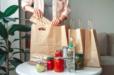 Kadın bağış için yiyecek paketliyor. Kese kağıdına, fotokopi alanı da boş.