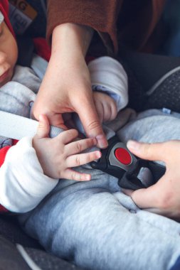 Annesi, küçük çocuğunun oturduğu koltuğa emniyet kemeri takıyor.