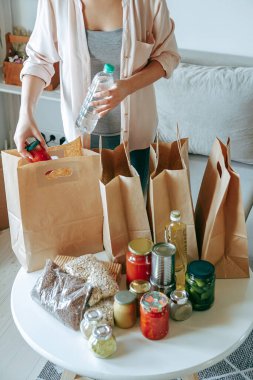 Kadın bağış için yiyecek paketliyor. Kese kağıdına, fotokopi alanı da boş.