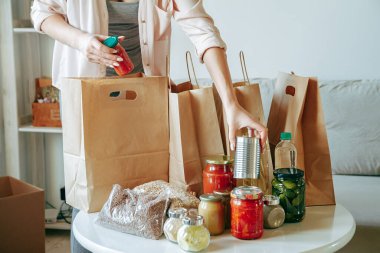 Kadın bağış için yiyecek paketliyor. Kese kağıdına, fotokopi alanı da boş.