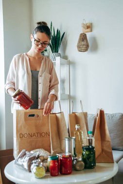 Kadın bağış için yiyecek paketliyor. Kese kağıdına, fotokopi alanı da boş.
