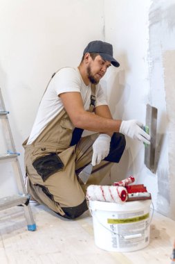 Elinde spatulası olan erkek ressam evde tamirat yapıyor. Oda yenileme konsepti.