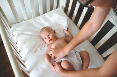 Genç bir anne, yatağına uzanmış küçük oğluna bakar.