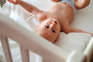 Şirin çocuk tahta bir bebek yatağında yatıyor.