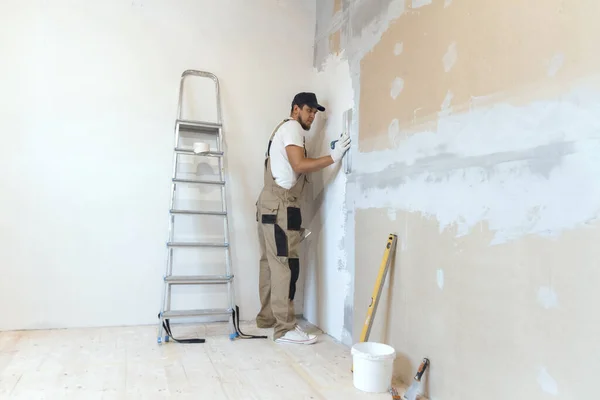 Male painter with a spatula in his hands makes repairs in home. Room renovation concept.