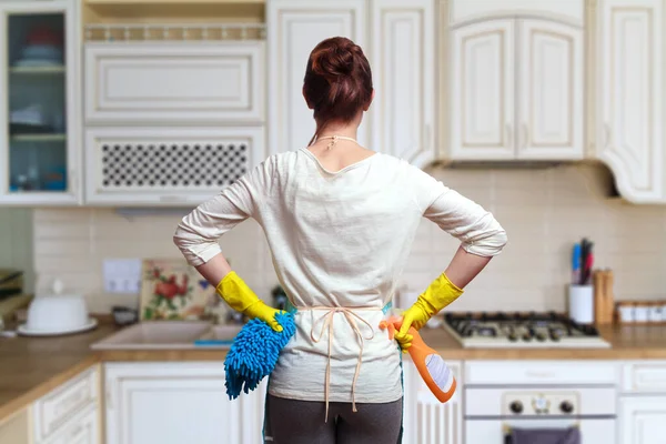 Young woman preparing to clean the kitchen at home. Cleaning service concept.