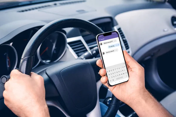 Young man driving a car with a phone in his hand. Multitasking. Don\'t text and drive