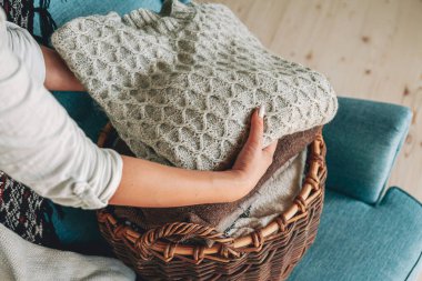 Kadınların elleri bir sepet içinde kalın örülü kazak yığını katlar.