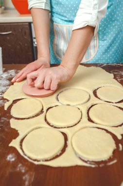 Genç kadın mutfakta yemek pişiriyor, hamuru pişirmek için hazırlıyor.