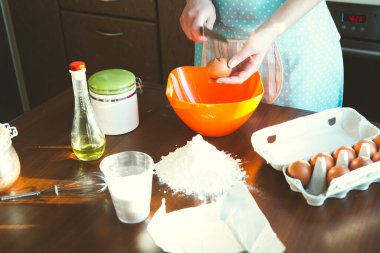 Genç kadın mutfakta yemek pişiriyor, hamuru pişirmek için hazırlıyor.