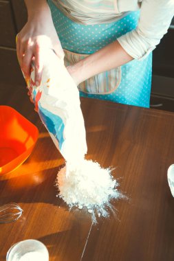 Kadın yemek pişirmek için masaya un döker.