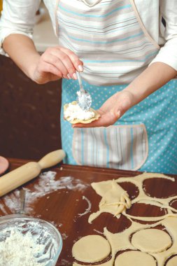 Genç kadın mutfakta yemek pişiriyor, hamur işini pişiriyor, turtaya süzme peynir ekliyor.