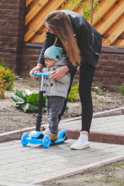 Çocuk ve anne dışarıda scooterlarla oynuyorlar. Çocuk için aktif eğlence ve açık hava sporu.