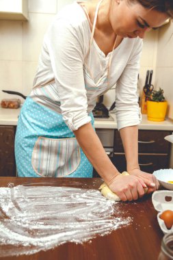 Genç kadın mutfakta yemek pişiriyor, hamuru pişirmek için hazırlıyor.