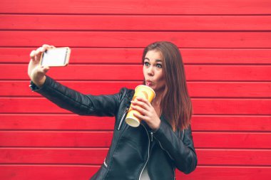 Arka plandaki kırmızı ahşap duvarda izole edilmiş akıllı telefon kullanan genç kadınların portresi. .