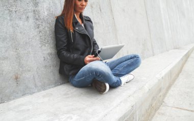 Genç kadın tablet ya da dizüstü bilgisayarı elinde tut.