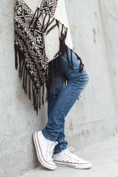 ジーンズと暖かいセーターを着た若い女の子の足は コンクリートの壁に立って — ストック写真