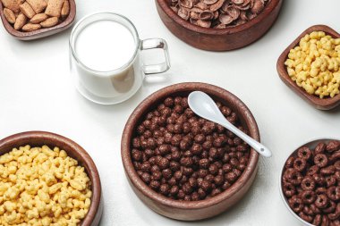 Farklı kahvaltılık gevrek ürünleri ve bir bardak sütle dolu bir kase.