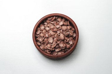 Beyaz arka planda çikolatalı, hızlı kahvaltı gevreği olan ahşap kase.