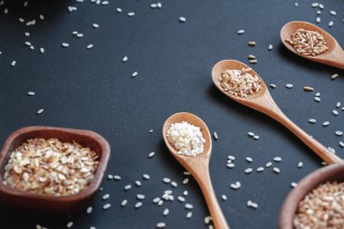 Ahşap kaselerde farklı pirinç çeşitleri ve tahıl gevrekleri ve bambu kaşığı.