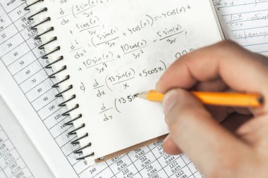 Matematik formülleri, elinde bir adam tutan bir defterde kurşun kalemle yazılır. Matematik problemleri.