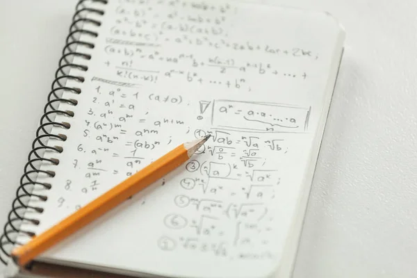 Math formulas are written in pencil on piece of paper, math problems