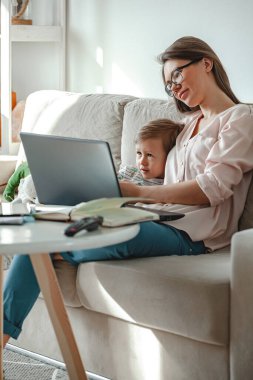 Evde ve evde çalışma kavramı, evde dizüstü bilgisayarla çalışma, yakınlarda oynayan çocuk