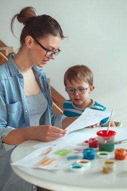 Anne ve çocuk evde bir köpekle birlikte resim yapıyorlar.